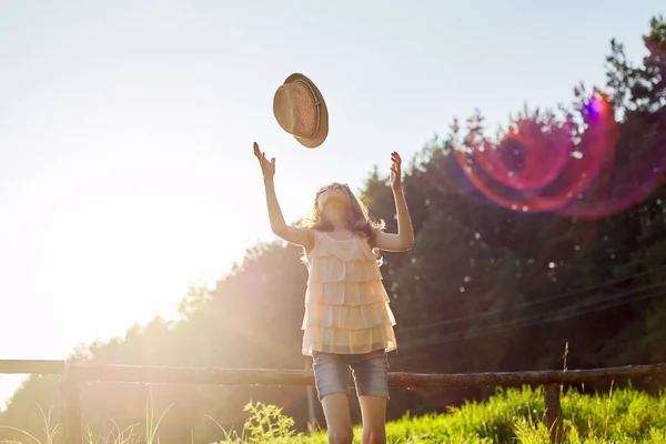 Chica feliz disfrutando de vacaciones de verano, niño en la naturaleza en el prado verde jugando con sombrero —  Fotos de Stock