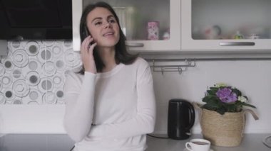  Cep telefonuyla konuşan genç bir kadın, mutfakta evde bir kadın.