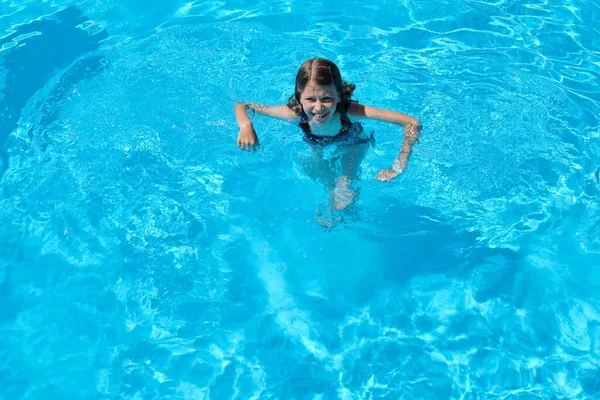 El niño se divierte en una piscina al aire libre, niña nada, bucea, juega en el agua, fondo azul —  Fotos de Stock