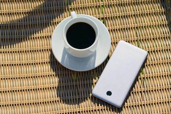 Вид сверху на чашку кофе и смартфон на плетеном фоне — стоковое фото
