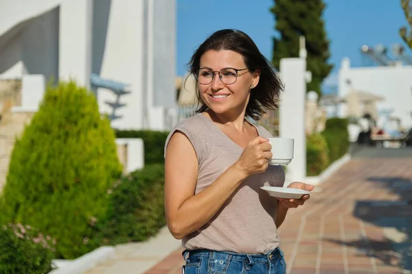 Mulher madura em óculos com xícara de café andando ao ar livre — Fotografia de Stock