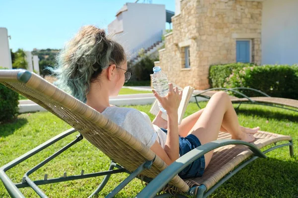 Teenager dívka relaxační venku, čtení knihy a pitné vody — Stock fotografie