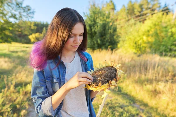 Ung kvinna med mogen solrosor i handen — Stockfoto