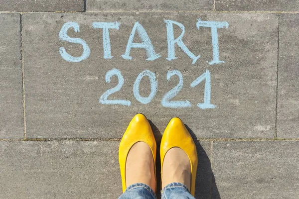 Початок концепції 2021 року, вид зверху на жіночі ноги і текст, написаний крейдою на сірому тротуарі — стокове фото