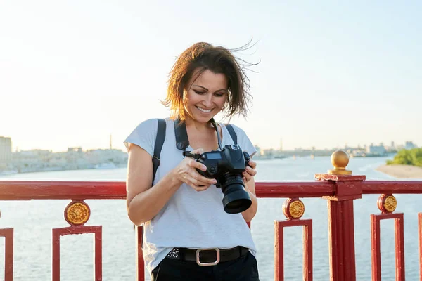 Mature female photographer with professional camera and backpack — Stock Photo, Image