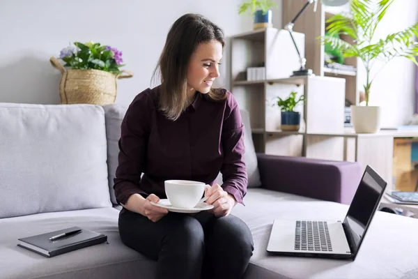 Jeune femme d'affaires avec ordinateur portable, tasse de café assis sur le canapé — Photo