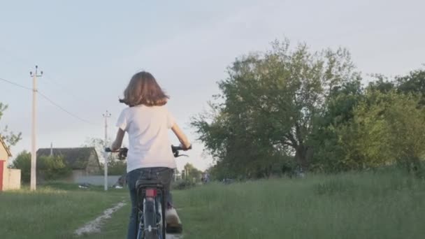 Kid girl jeździ na rowerze, dziewczyny pierwszy sukces rowerowy, zachód słońca wiejskiej drogi, naturalne tło krajobraz, widok z tyłu — Wideo stockowe