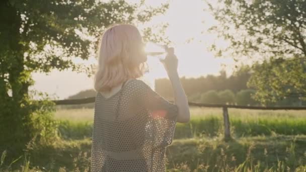 Nastolatka picie szkła z czystej wody mineralnej, zachód słońca słońce natura tło — Wideo stockowe