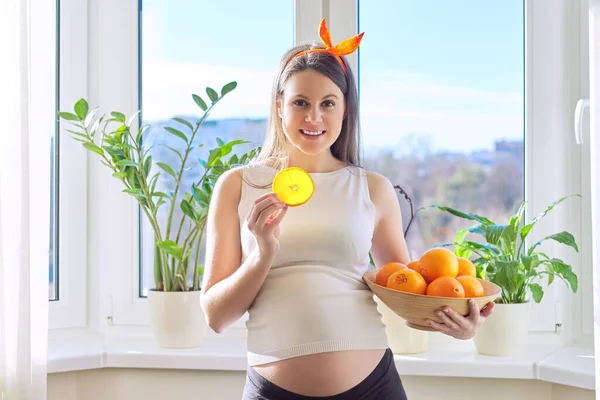 Alimentos vitamínicos saudáveis, bela jovem grávida feliz com laranjas — Fotografia de Stock