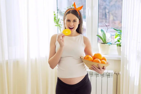 Healthy vitamin food, Beautiful happy pregnant young woman with oranges