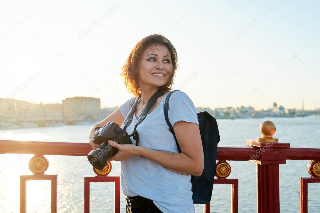 Mature female photographer with professional camera and backpack