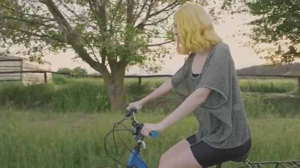 Vacaciones activas de verano, feliz adolescente monta bicicleta, hipster de moda con el pelo teñido disfruta de montar a caballo y la naturaleza, fondo del campo — Vídeos de Stock