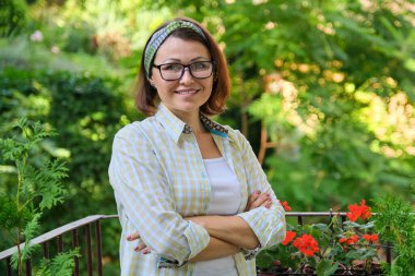 Orta yaşlı mutlu bir kadının portresi, kollarını kavuşturmuş kendine güvenen bir kadın.