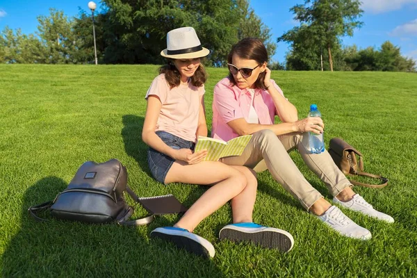 Mom and daughter teenager student together sitting on the green lawn — Stock Photo, Image