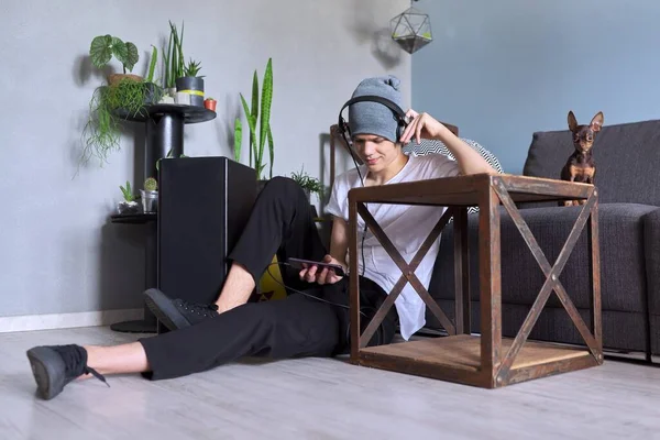 Teenage chlapec hipster ve sluchátkách s chytrým telefonem poslech hudby — Stock fotografie