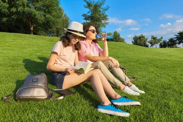 Mom and daughter teenager student together sitting on the green lawn — Stock Photo, Image