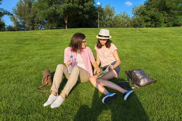 Äiti ja tytär teini opiskelija yhdessä istuu vihreällä nurmikolla — kuvapankkivalokuva