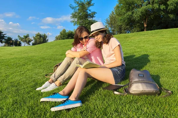 Mom and daughter teenager student together sitting on the green lawn — Stock Photo, Image