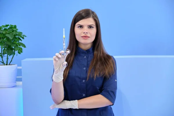 Bela jovem médica com seringa na mão, enfermeira feminina olha na câmera — Fotografia de Stock