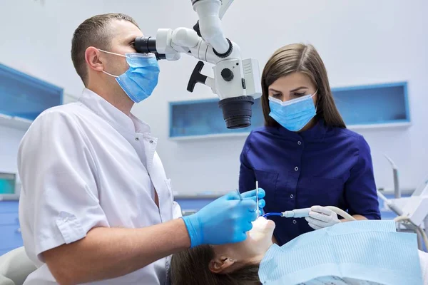 Médico dentista masculino que trata los dientes con instrumentos de microscopio dental — Foto de Stock
