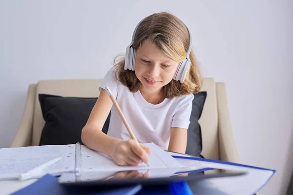 Kind met digitale tablet en koptelefoon schrijven in notebook — Stockfoto