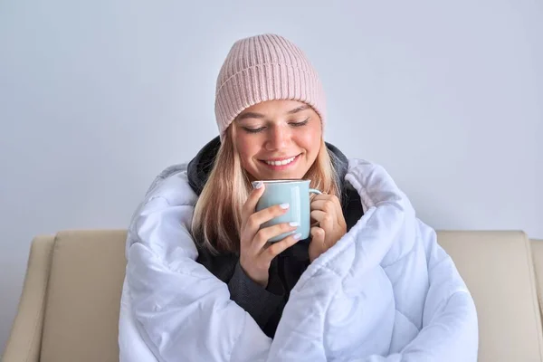 Fría temporada de invierno de otoño, adolescente sentada en el sofá bajo una manta caliente —  Fotos de Stock