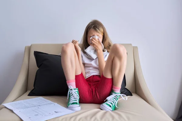 Temporada de gripe, niño estornudando en el pañuelo, niña sentada en casa escribiendo en un cuaderno — Foto de Stock