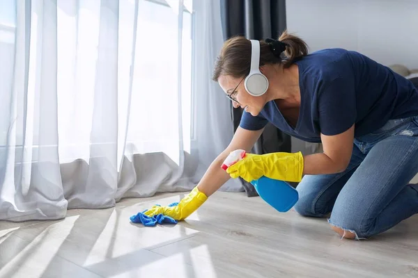 Hausreinigung positiv, Frau mit Kopfhörerhandschuhen reinigt Boden — Stockfoto