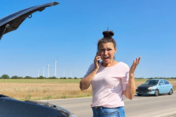 Woman on the roadside near broken car talking on cell phone — Stock Photo, Image