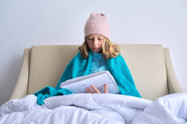 Saison froide, fille enfant à la maison en bonnet tricoté sous couverture chaude — Photo