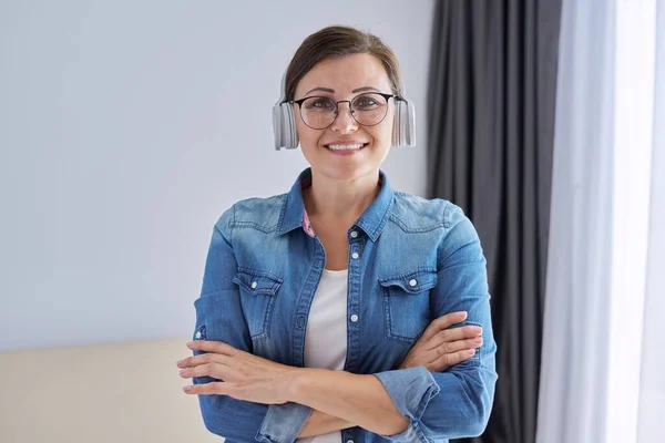 Portrait de femme mature d'âge moyen confiante portant des lunettes et des écouteurs — Photo