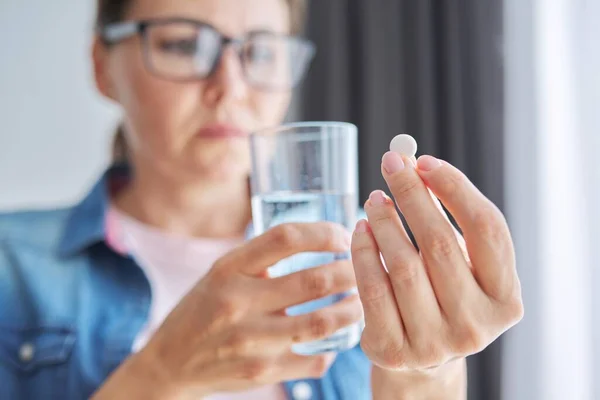 Ältere Frau mittleren Alters zu Hause mit Pille und Glas Frischwasser — Stockfoto