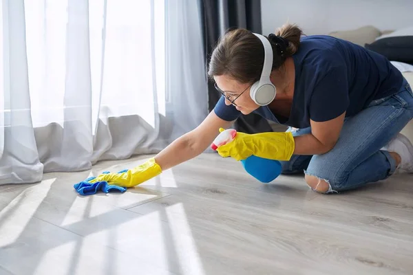 Hausreinigung positiv, Frau mit Kopfhörerhandschuhen reinigt Boden — Stockfoto