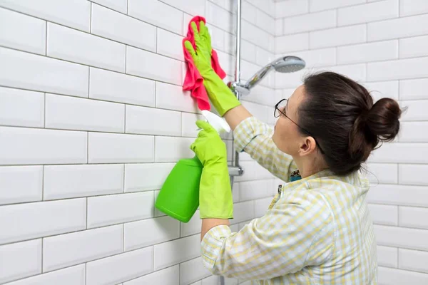Limpieza del cuarto de baño, ama de casa lavado pared de baldosas blancas con detergente y trapo —  Fotos de Stock