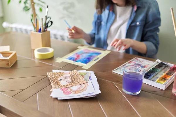 Malowanie nastolatka z akwarelami, siedzi w domu przy stole — Zdjęcie stockowe