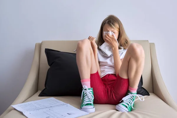 Temporada de gripe, niño estornudando en el pañuelo, niña sentada en casa escribiendo en un cuaderno — Foto de Stock