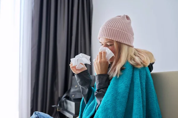 Teenager girl sneezing in handkerchief, female with symptoms of illness sitting at home — Stock Photo, Image