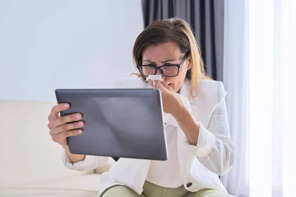 Sick business woman sneezing into handkerchief makes video call to doctor