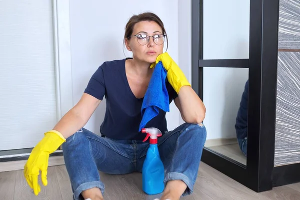 Sorgsen trött kvinna i handskar sitter på golvet klar rengöring — Stockfoto