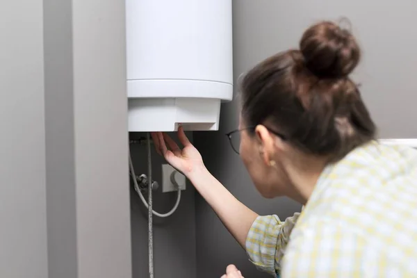 家用热水器，妇女调节电热水器的温度 — 图库照片