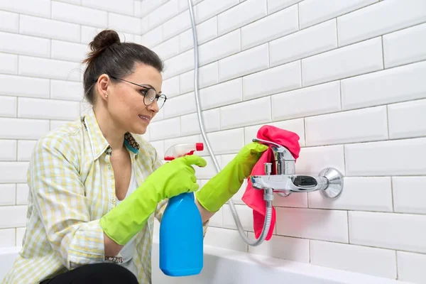 Vrouw in handschoenen met wasmiddel en vod doen badkamer schoonmaken — Stockfoto