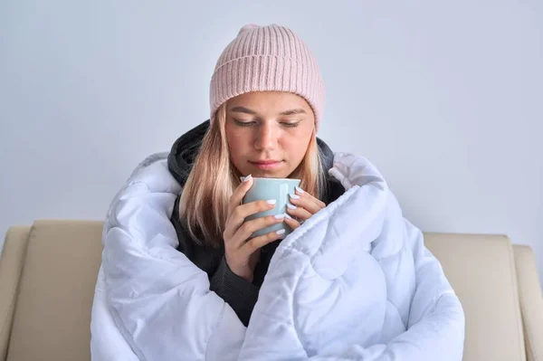Κρύο χειμώνα φθινόπωρο, έφηβος κορίτσι κάθεται στον καναπέ κάτω από ζεστή κουβέρτα — Φωτογραφία Αρχείου