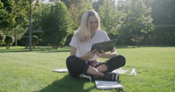 Vídeo conferência, menina adolescente estudante falando olhando para a tela do tablet digital sentado na grama — Vídeo de Stock