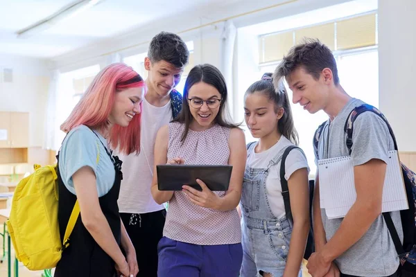Skupina dospívajících studentů a mladé učitelky s digitálním tabletem ve třídě — Stock fotografie