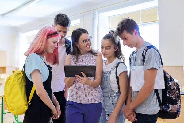 Grupo de estudiantes adolescentes y profesora joven con tableta digital en el aula —  Fotos de Stock