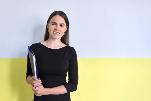 Young positive businesswoman with folder in hand smiling looking at camera — Stock Photo, Image