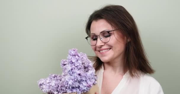 Glücklich lächelnde reife Frau mit Blumenstrauß auf grünem Pastell-Hintergrund — Stockvideo