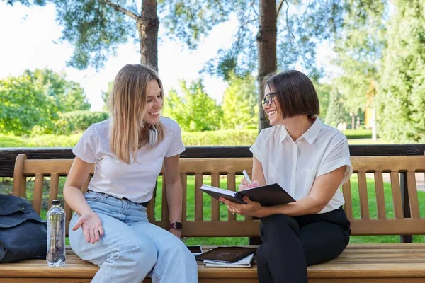 Mujer trabajadora social hablando con chica adolescente escribiendo entrevistas en cuaderno —  Fotos de Stock