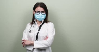 Tıbbi koruyucu maskeli, steteskoplu, kendinden emin, olgun bir doktorun portresi.