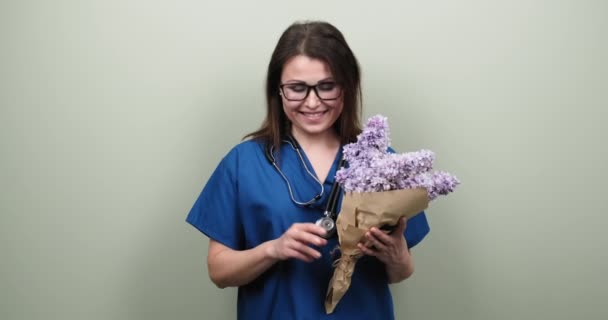 Porträtt av kvinnlig läkare visar ok hand tecken, glad leende läkare med bukett blommor — Stockvideo